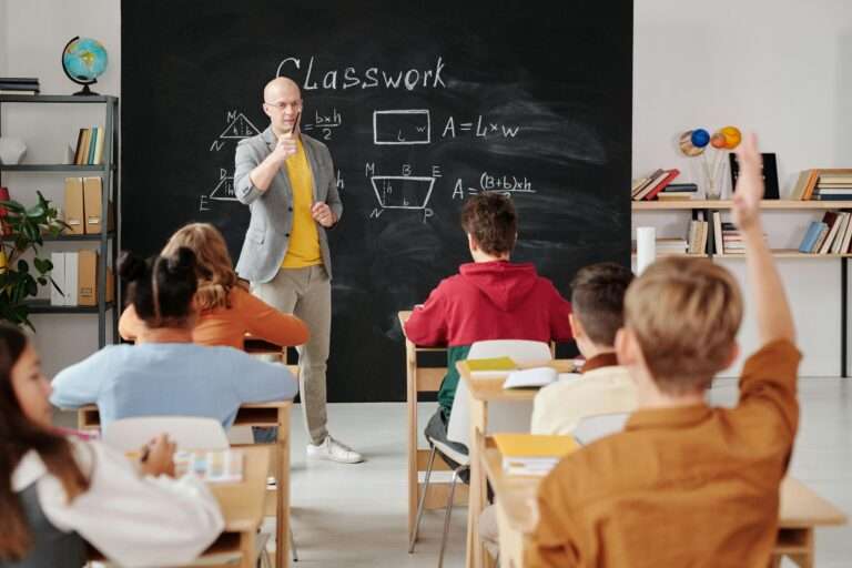 Teacher is standing in front of a chalkboard teaching a classroom of middle school students.